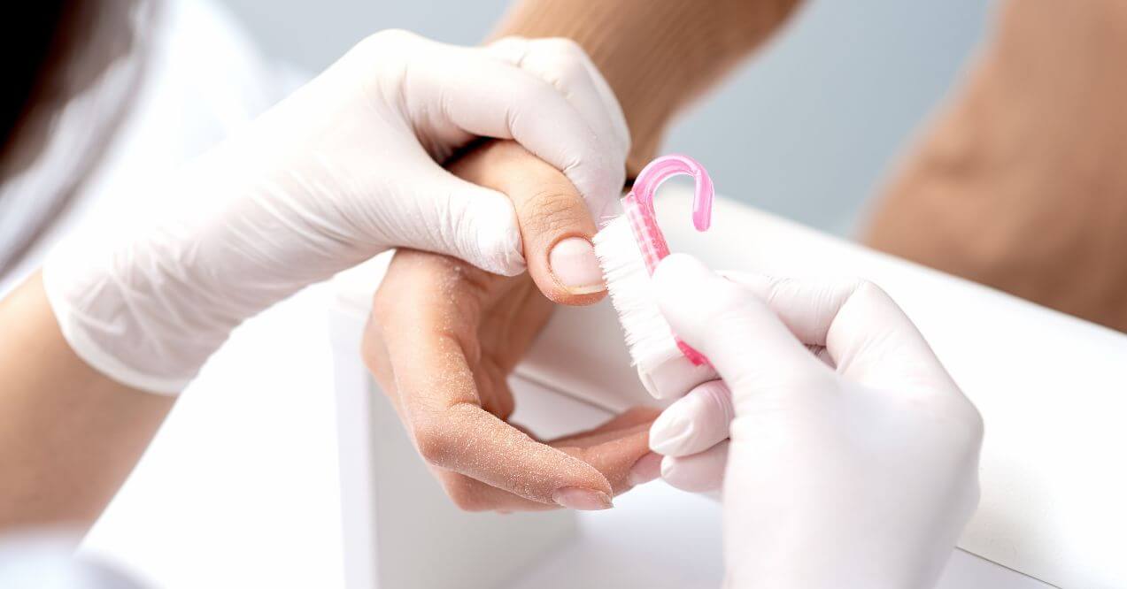 Close-up of a hand being cleaned during a professional nail care treatment.