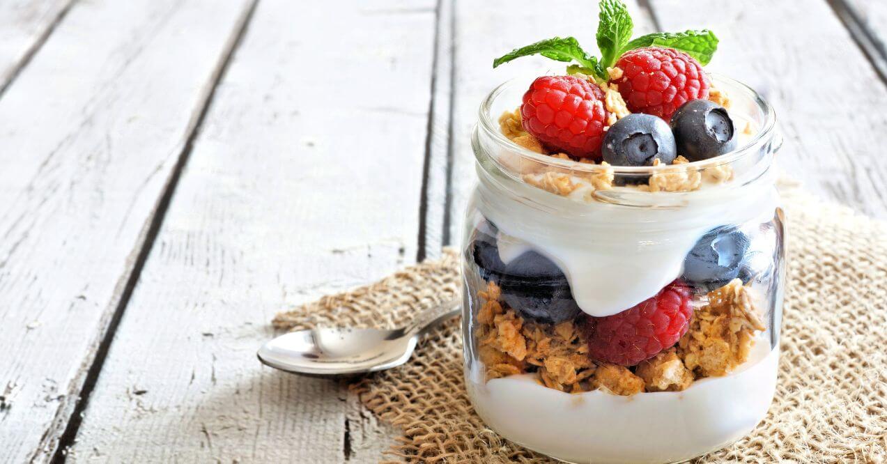 Layered yogurt parfait with raspberries, blueberries, and granola in a jar.