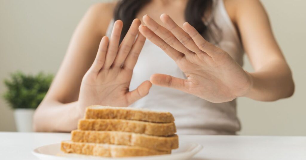 A person pushing away a plate of bread slices.