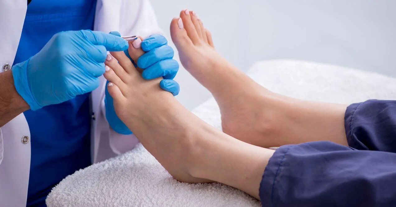 Podiatrist examining and cleaning a patient’s feet during a check-up.