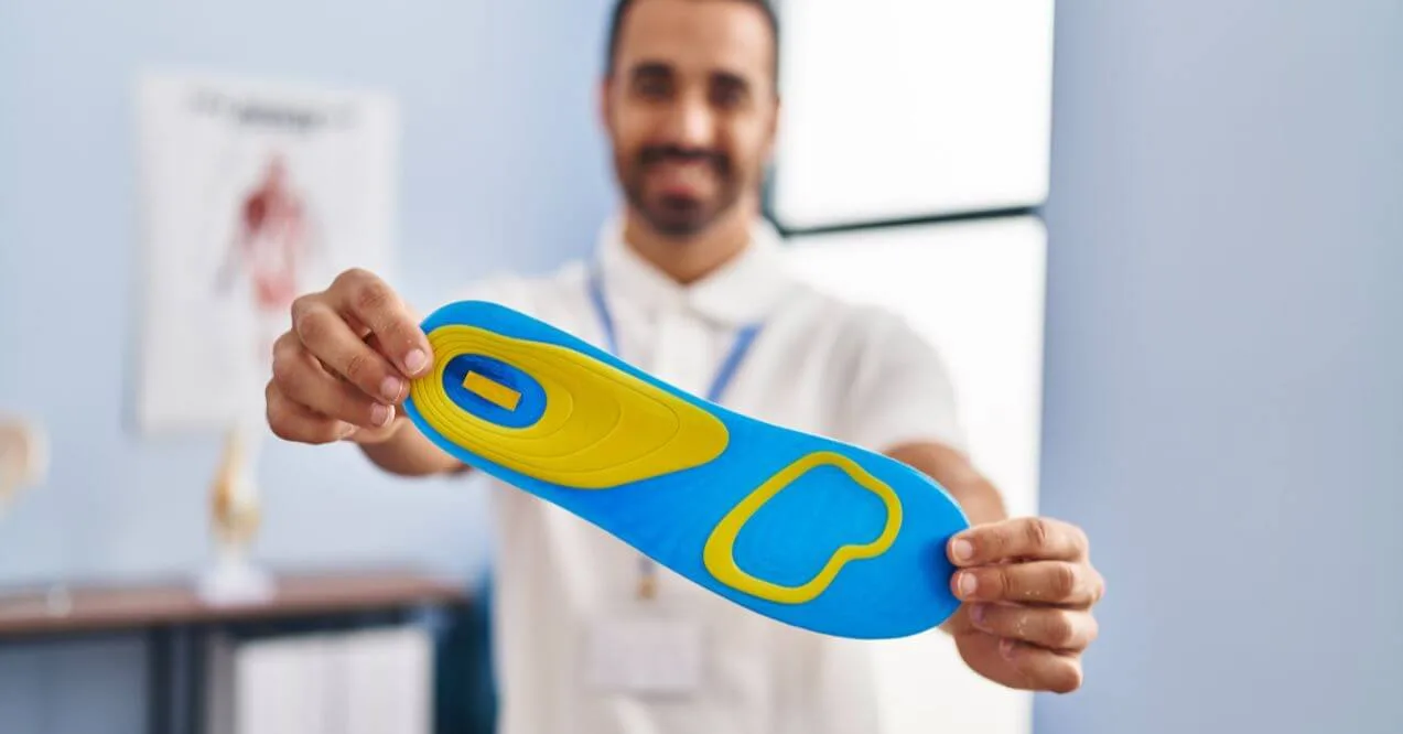 Man holding an orthotic insole to address foot health concerns.