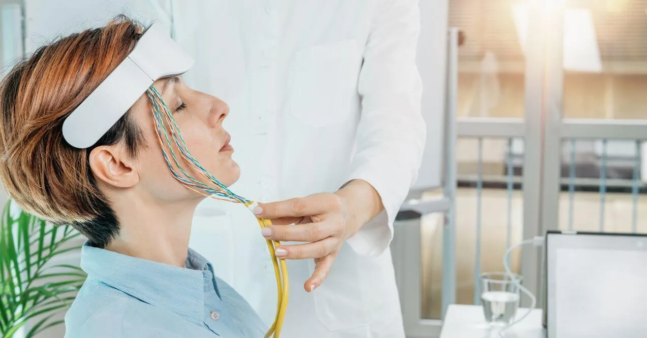 Woman undergoing biofeedback therapy with sensors attached to her head.