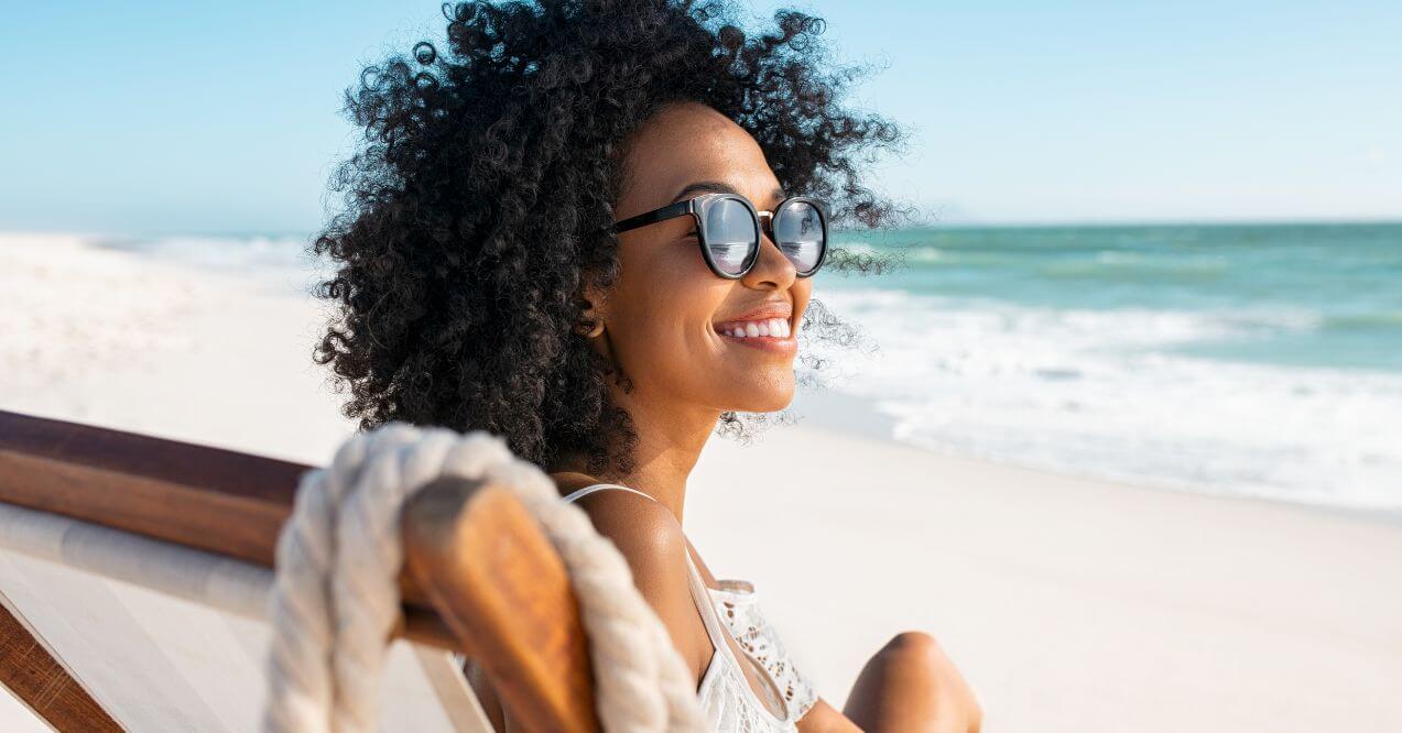 Woman wearing sunglasses relaxing by the beach.