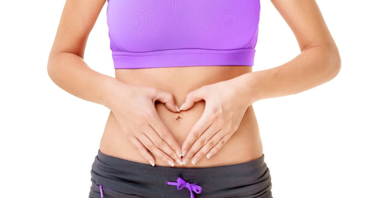 Woman forming heart shape over stomach for gut health.