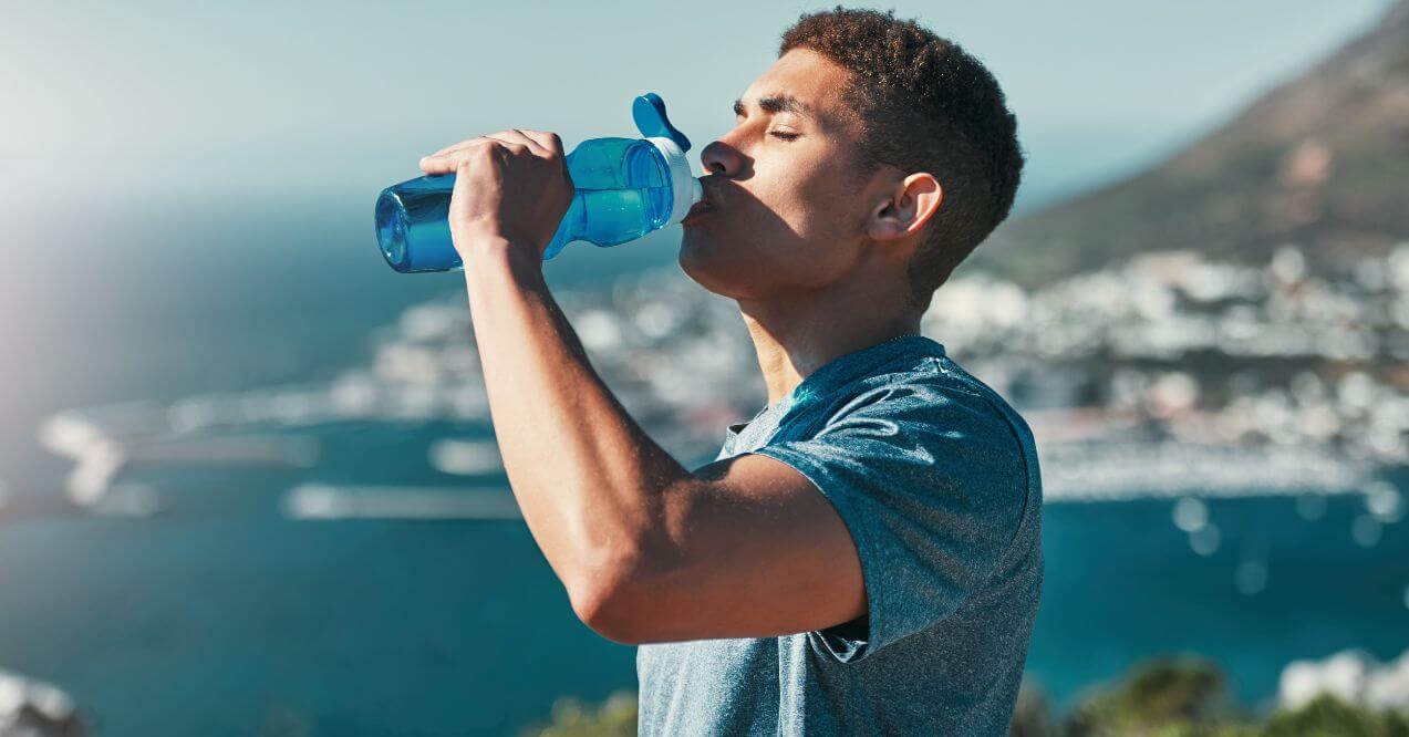 Man drinking water outdoors to stay hydrated.