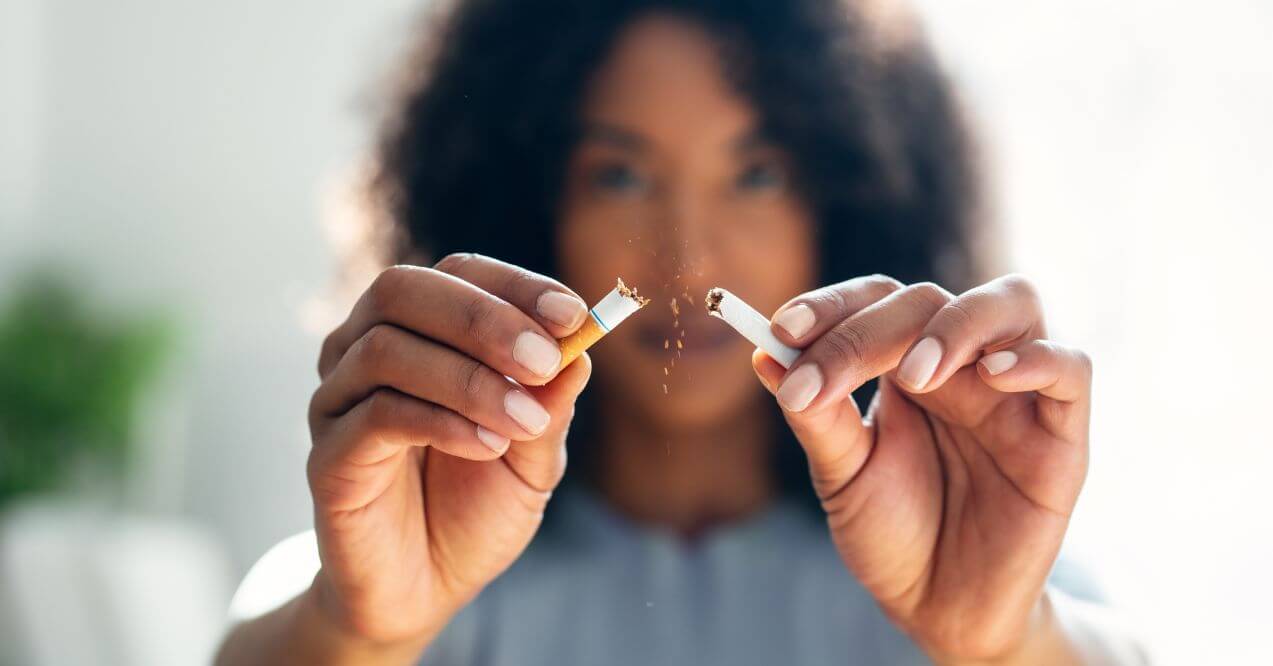 Breaking a cigarette in half to symbolize quitting smoking.