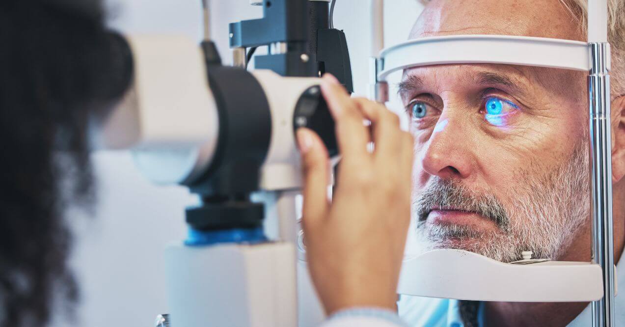 Older man undergoing an eye exam with specialized equipment.