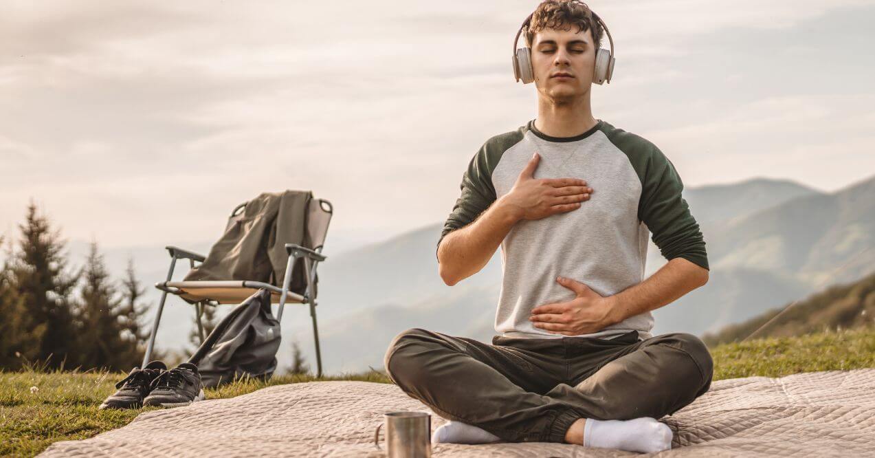 Man meditating outdoors for effective stress management.