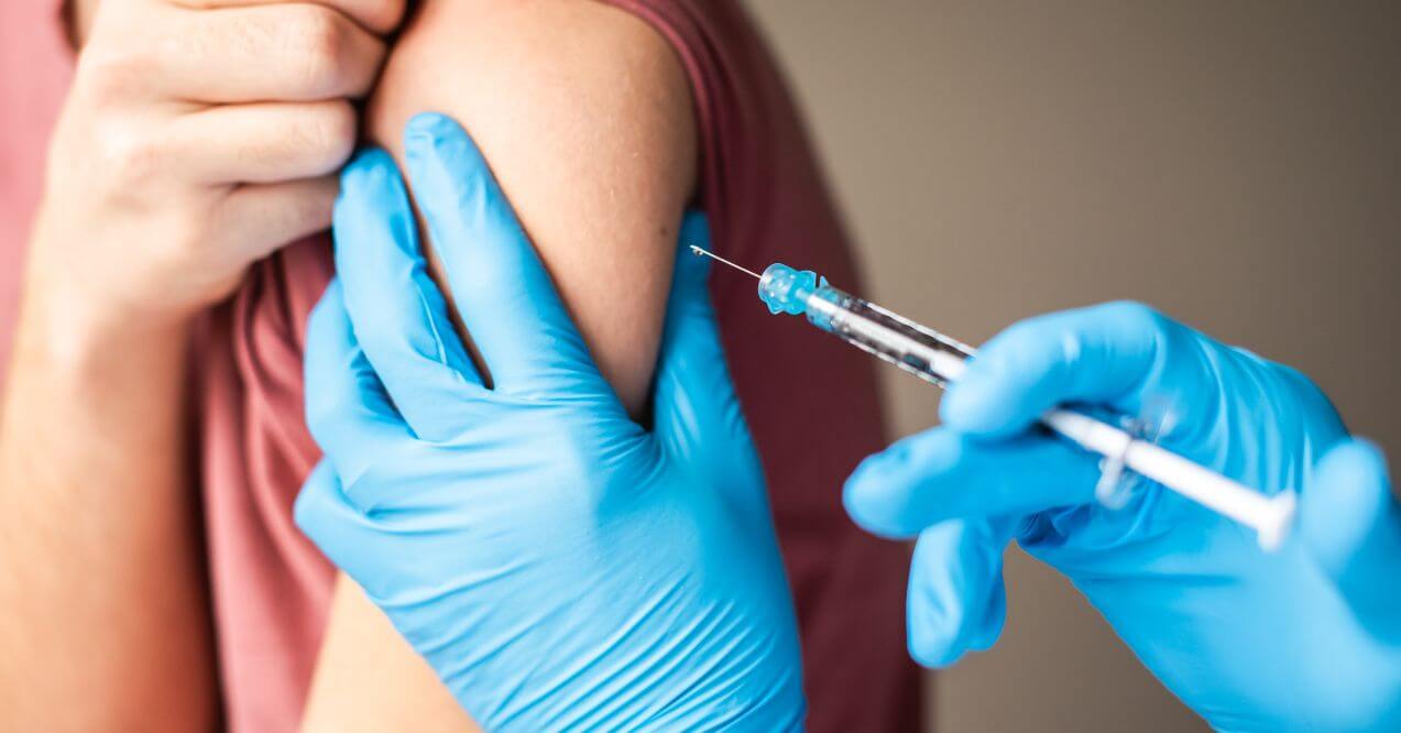 Close-up of a healthcare professional administering a vaccine shot into an arm.