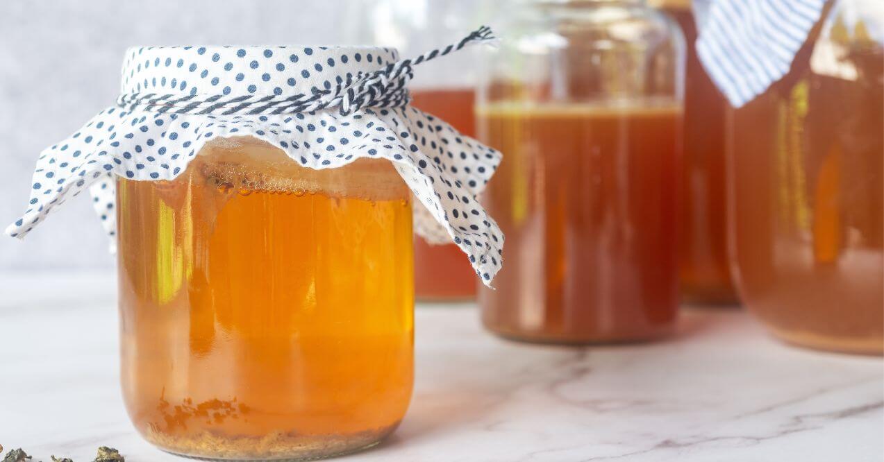 Homemade kombucha in glass jars with polka-dotted fabric covers.