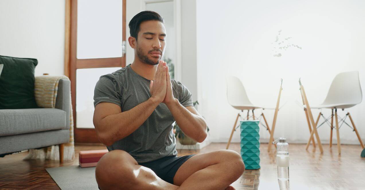 Man meditating at home to reduce stress.