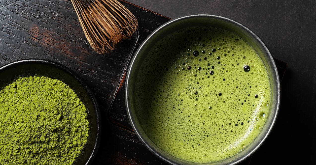 Traditional matcha tea preparation with a bamboo whisk and vibrant green matcha powder.