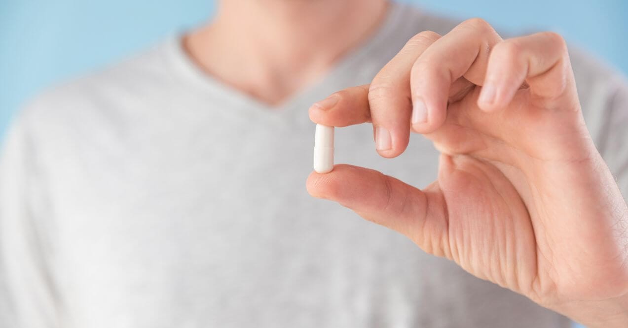 Person holding a pentadecanoic acid supplement for health support.