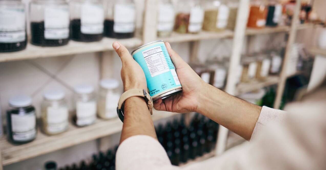 Person holding a product and reading its nutrition label in a store.