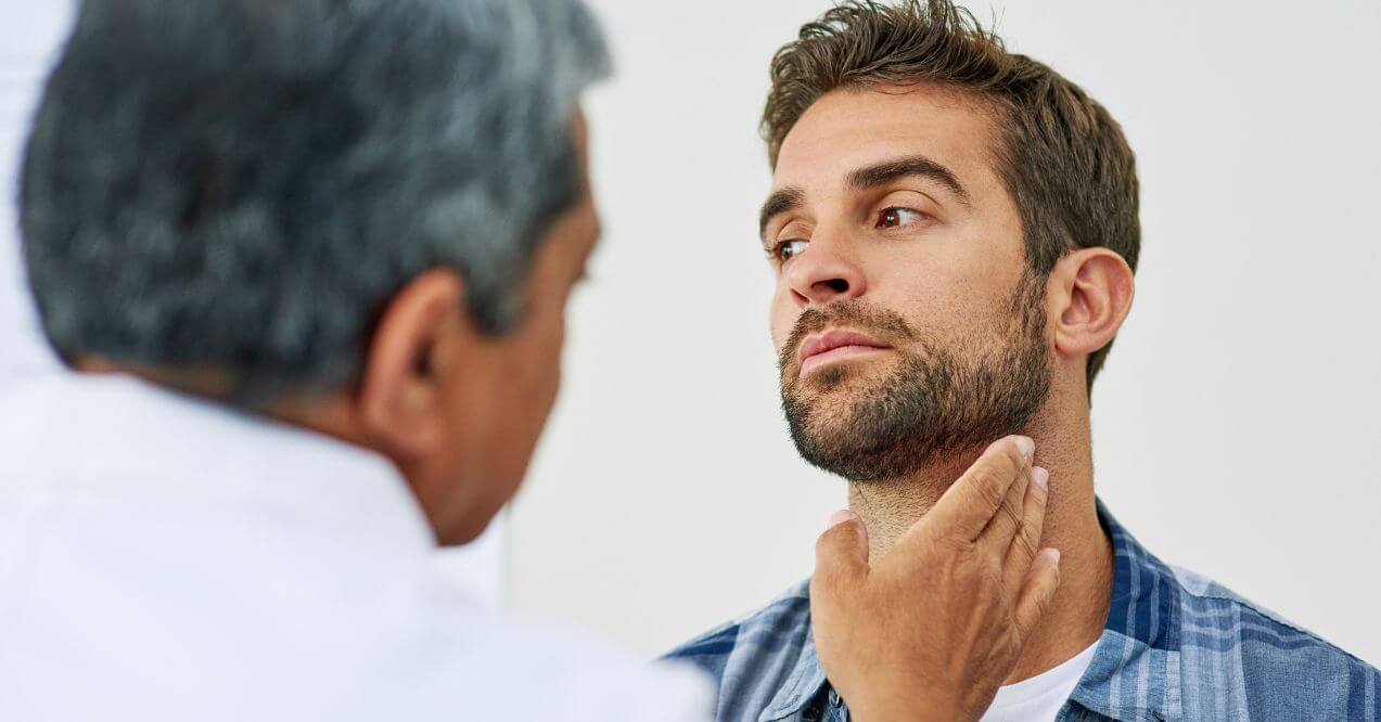 Doctor performing thyroid checkup on male patient.