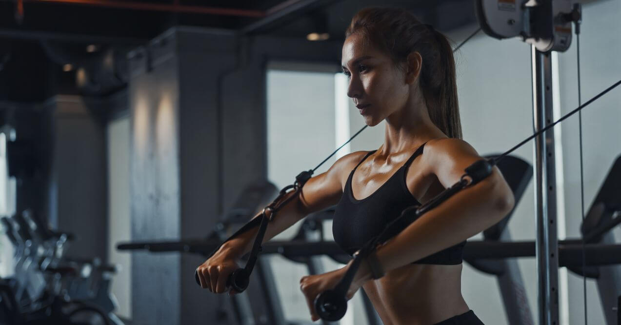 Woman performing a strength training exercise in a gym for improved fitness.