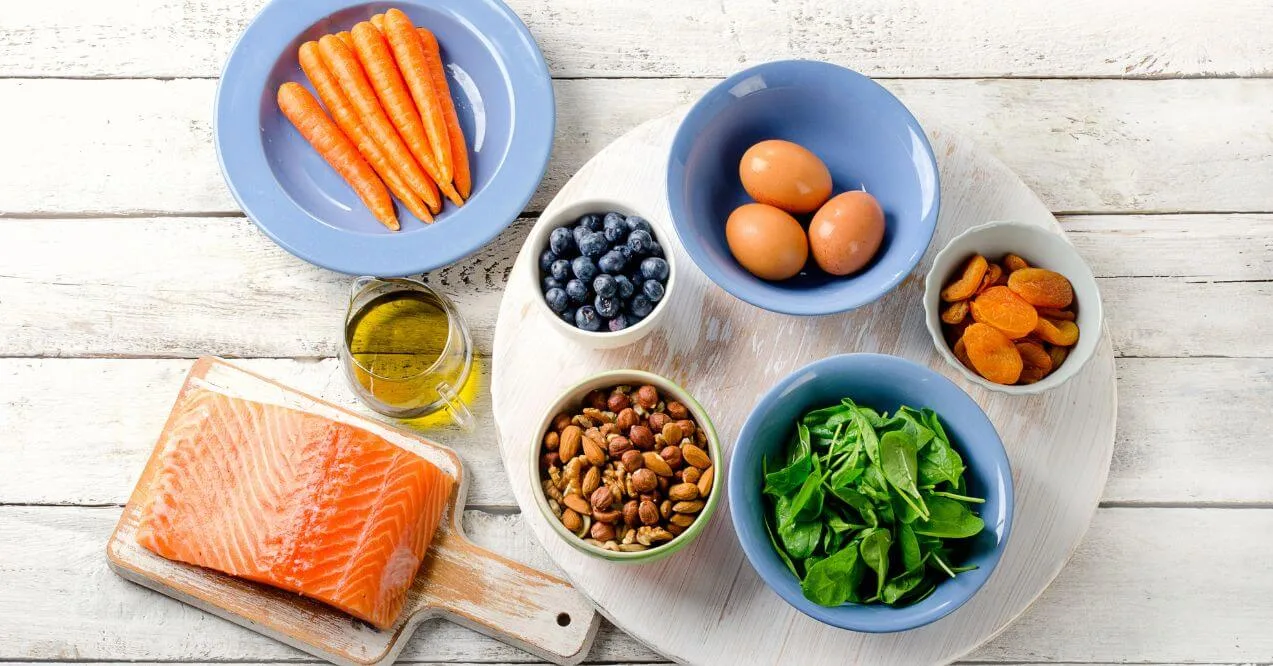 A selection of eye-healthy foods including salmon, eggs, carrots, and nuts.