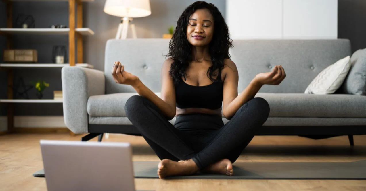 Woman meditating in a cross-legged pose in her living room.