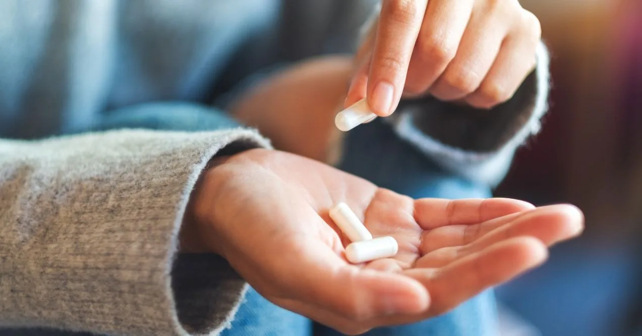 Person holding NMN supplement capsules in their hand, about to take them.