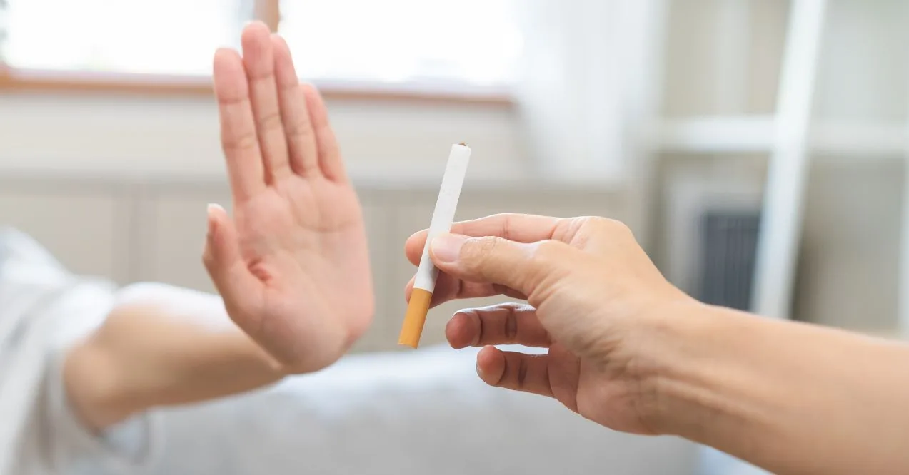 Person rejecting a cigarette with a hand gesture.