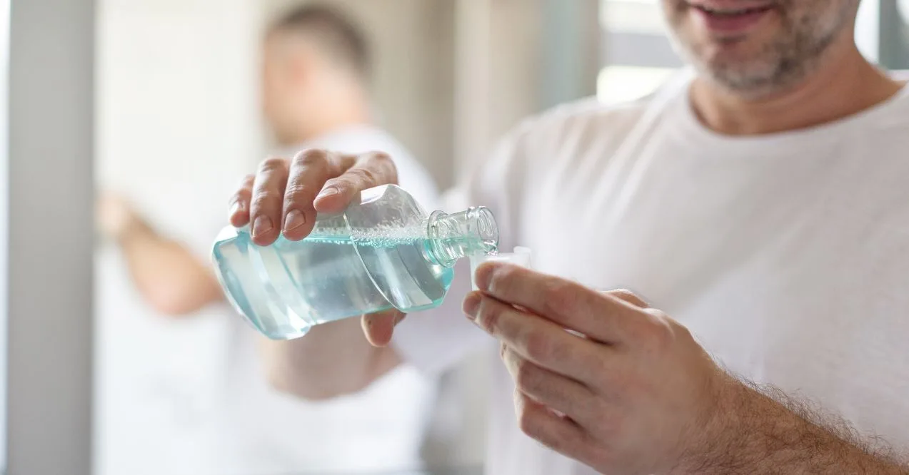 Man pouring mouthwash into a cap for rinsing.