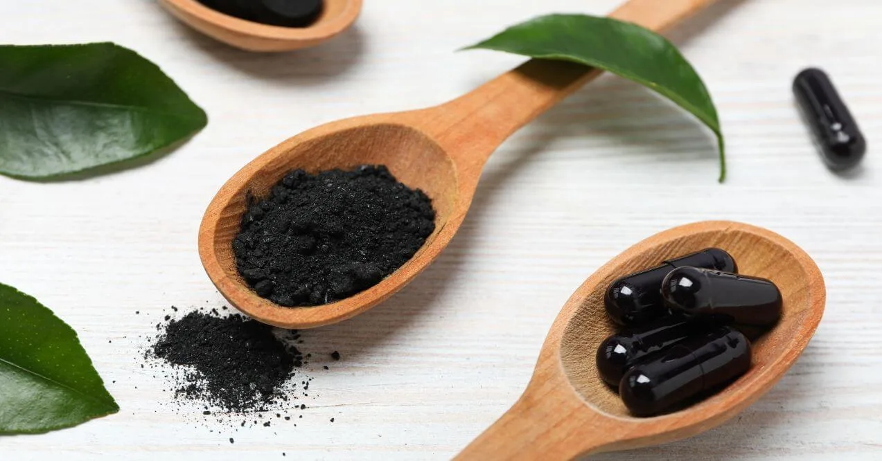 Wooden spoons filled with soil-based probiotics in powder and capsule form.