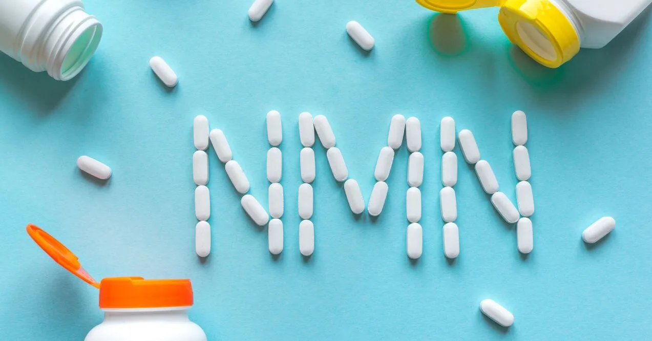 White capsules spelling out "NMN" on a blue background with supplement bottles nearby.