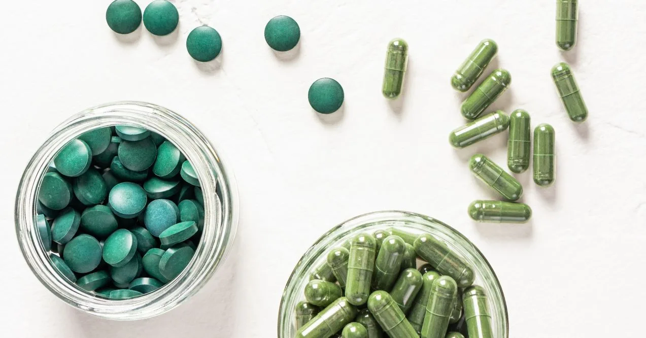 Two glass jars filled with capsules and tablets of organic probiotics on a white textured background.