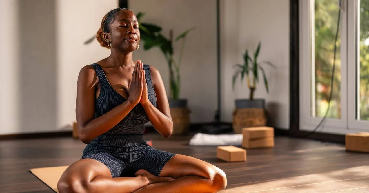 Woman meditating in a yoga pose in a peaceful indoor setting.
