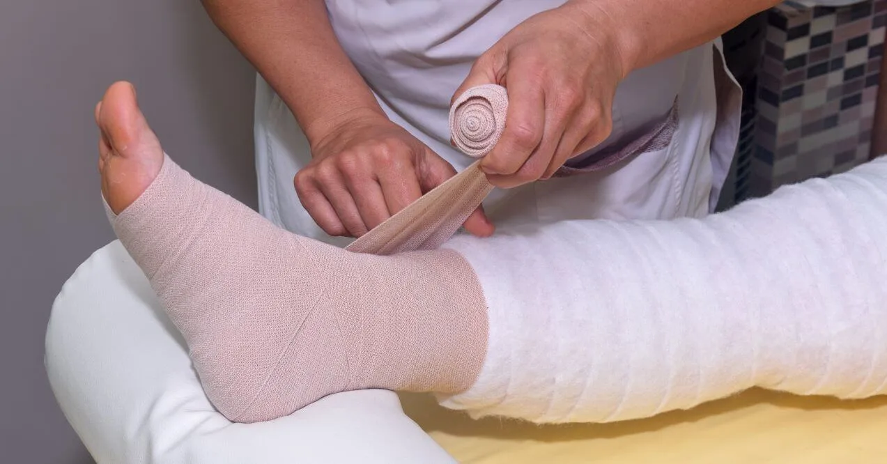 Therapist wrapping leg with bandages for lymphedema treatment