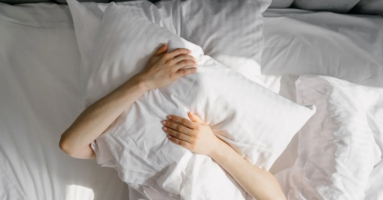 Female cover her head with cushion suffers from insomnia need sleeping pills, flat lay shot.