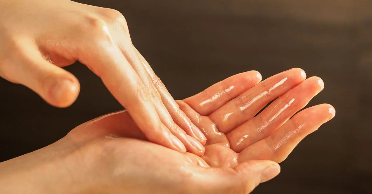 Hands applying oil to palm before starting self-massage