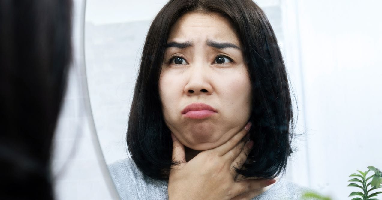 Woman examining her face in the mirror showing concern how to lose face fat