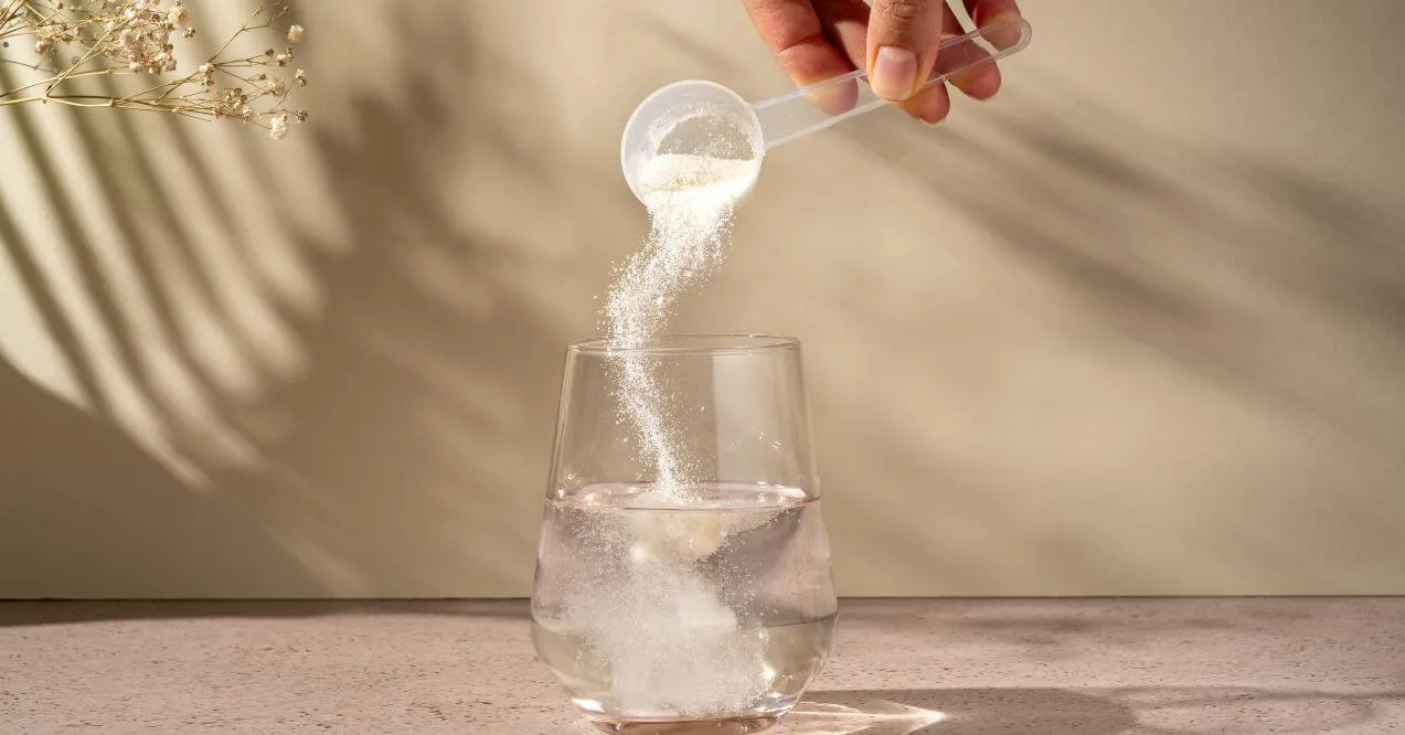 Hand adding a powdered supplement to a glass of water