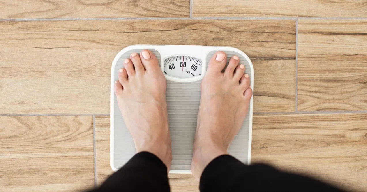 Person stepping on a weight scale with bare feet