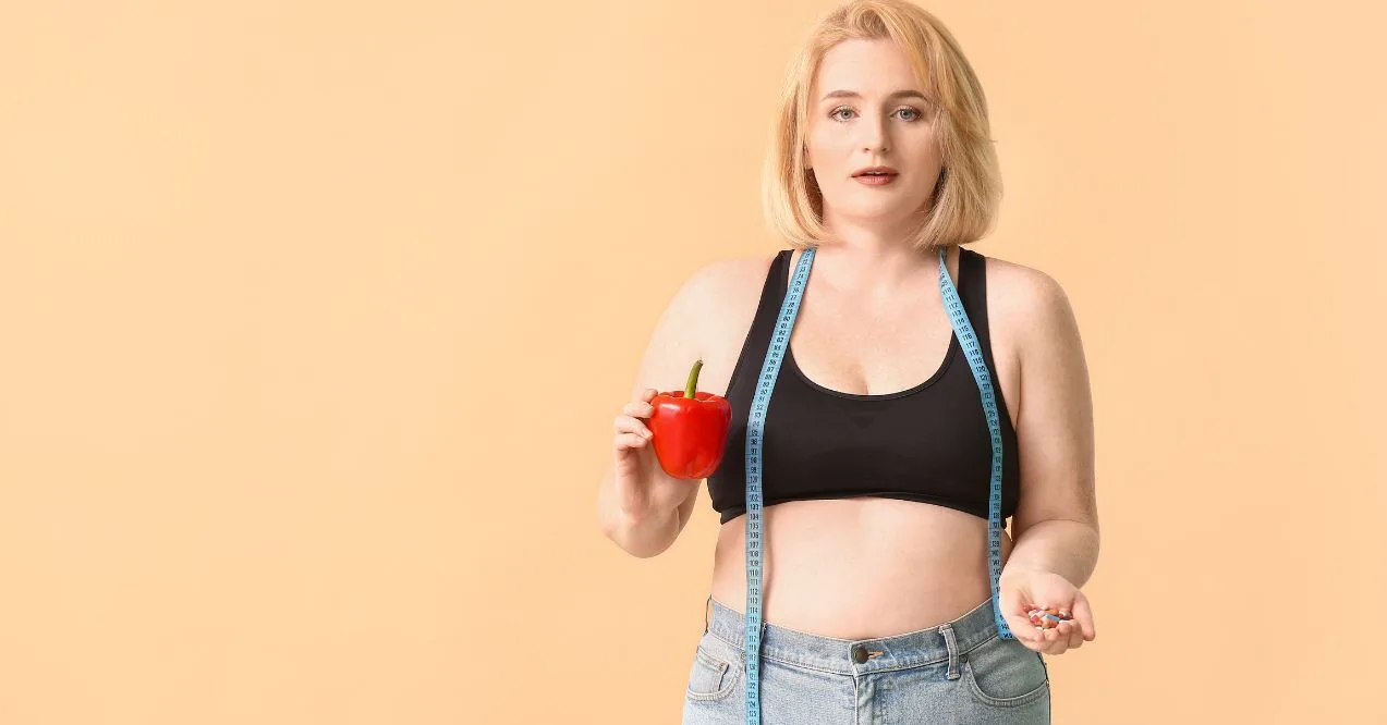 A woman with a measuring tape around her neck holding a red bell pepper and supplements wondering what is metabolic age.
