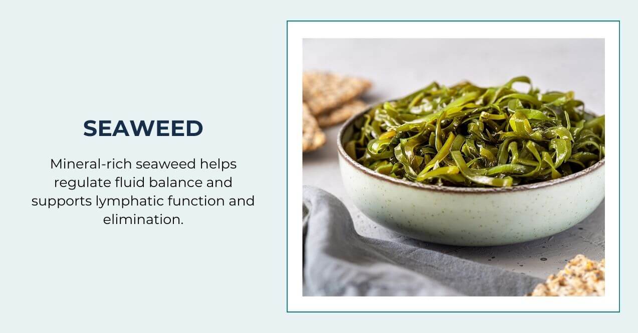 Bowl of fresh green seaweed next to crackers on a table.