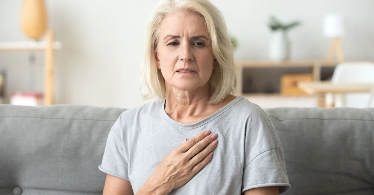 Close-up of an elderly woman holding her chest, reflecting on Parkinson's nerve effects.