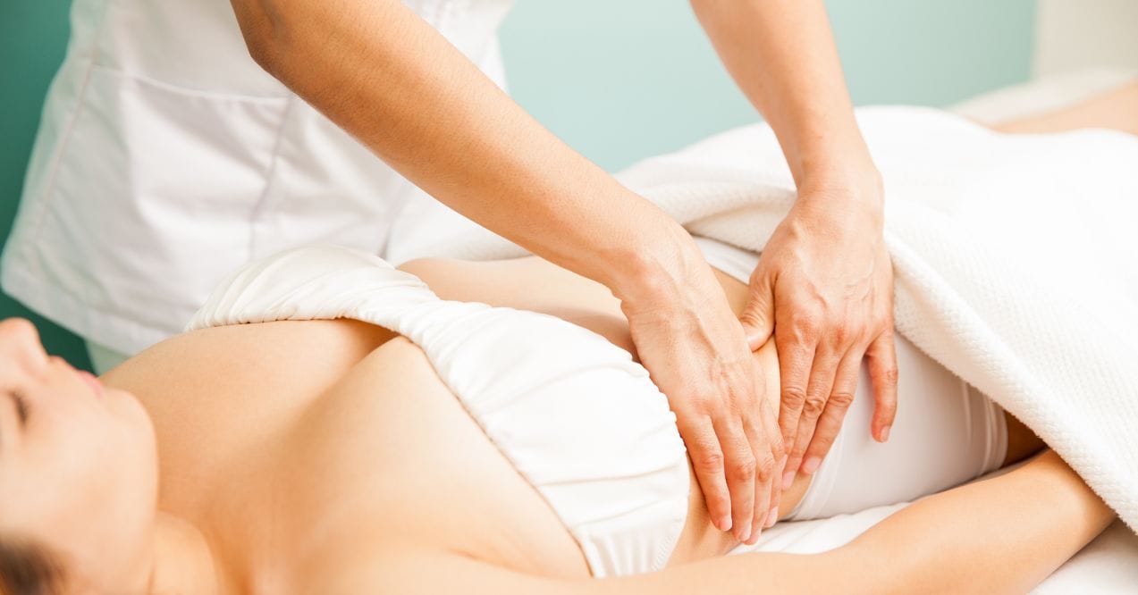 A professional performing lymphatic drainage massage on a client’s abdomen.