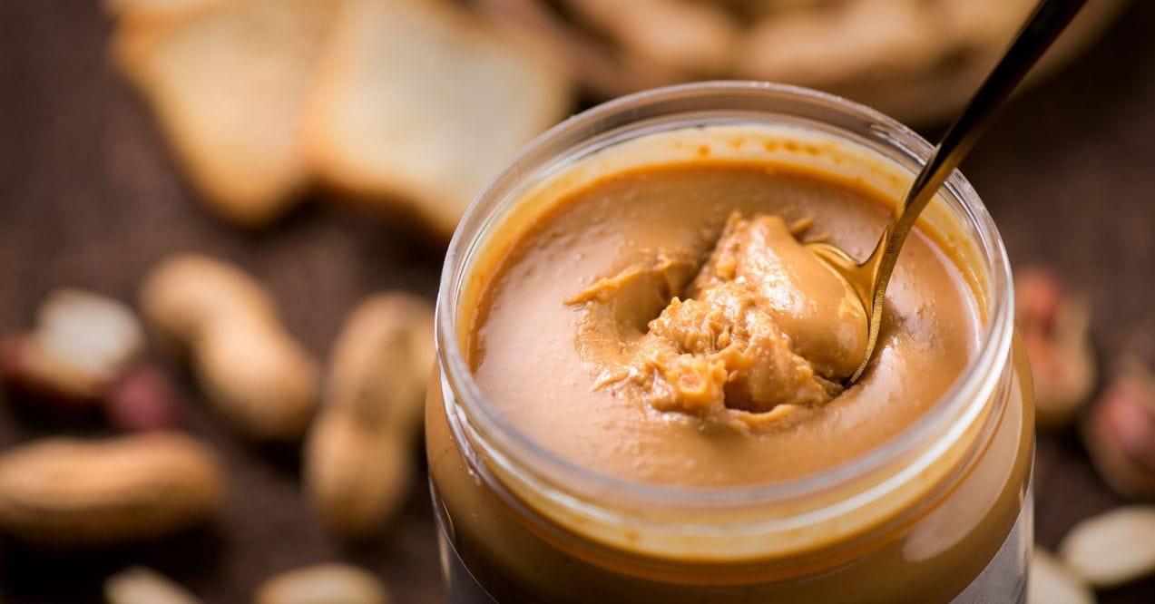 Close-up of peanut butter jar with spoon inside resembling the connection between peanut butter and lymphedema