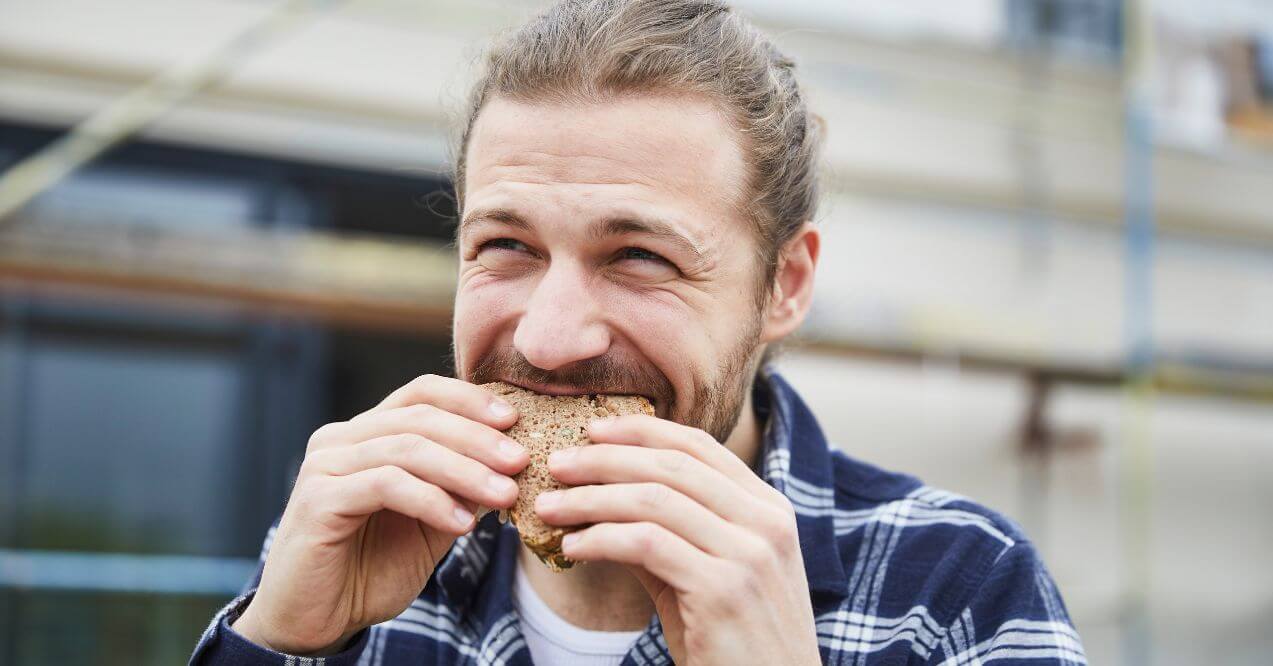 Man eating a sandwich resembling the topic: "Do men process carbs differently than woman"