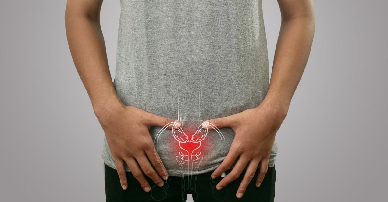 Man holding lower abdomen with prostate area highlighted in red wondering what causes enlarged prostate