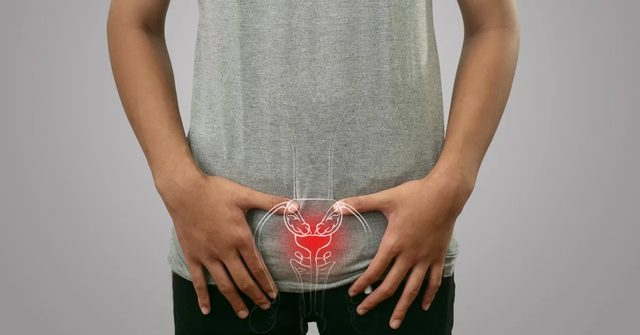 Man holding lower abdomen with prostate area highlighted in red wondering what causes enlarged prostate