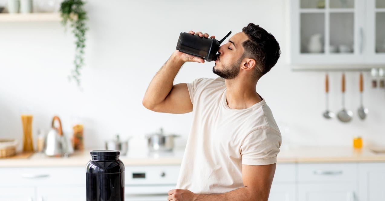 Man drinking a protein shake in the kitchen resembling can too much protein cause kidney stones