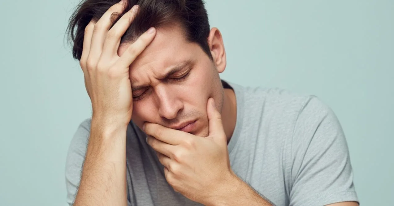 Man clutching head and jaw, grimacing with tooth pain and headache