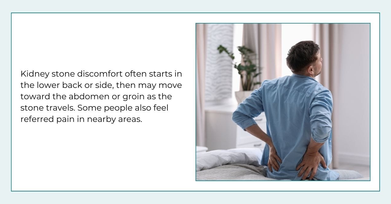 Man sitting on a bed holding his lower back, showing discomfort