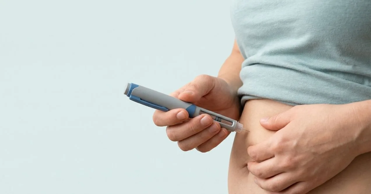 Person injecting a GLP-1 medication into the abdomen with an injector pen