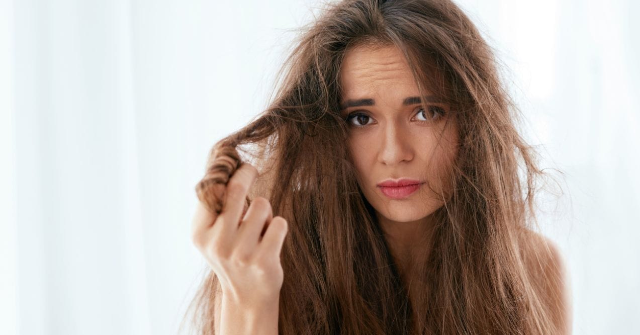 Woman examining hair shedding with a concerned expression