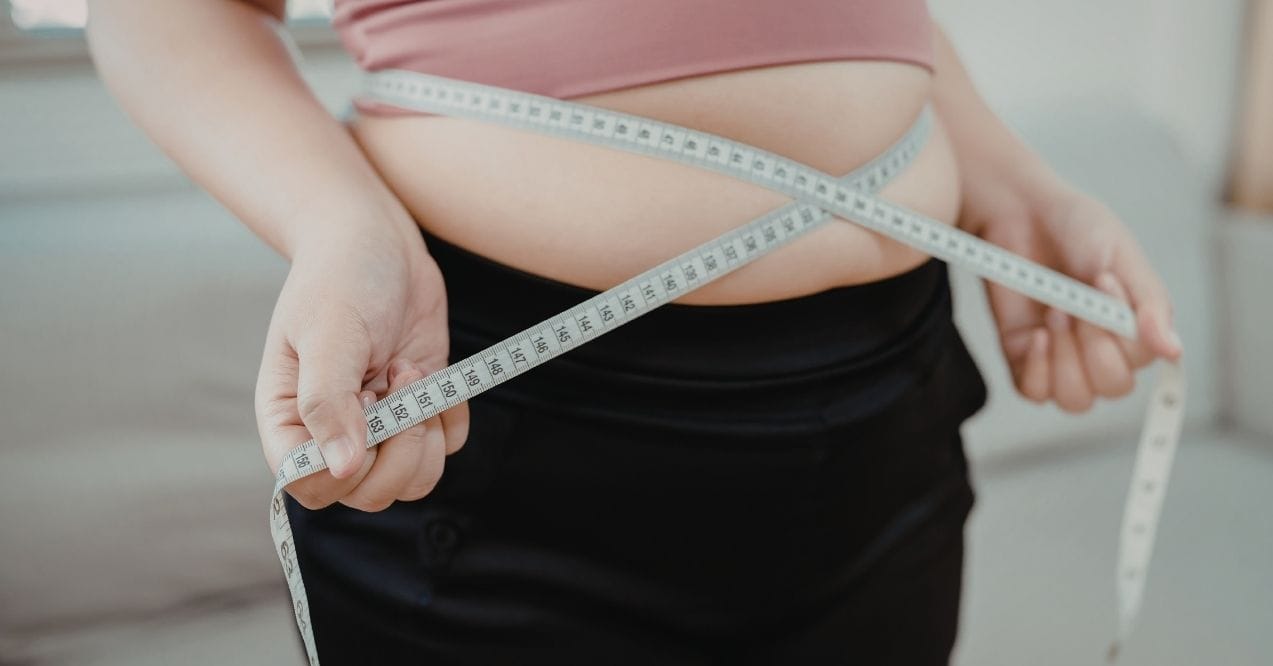 Close-up of a woman measuring her waist with a tape measure