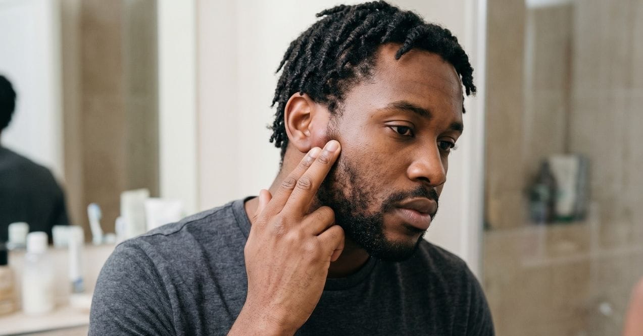 man touching swollen preauricular lymph nodes